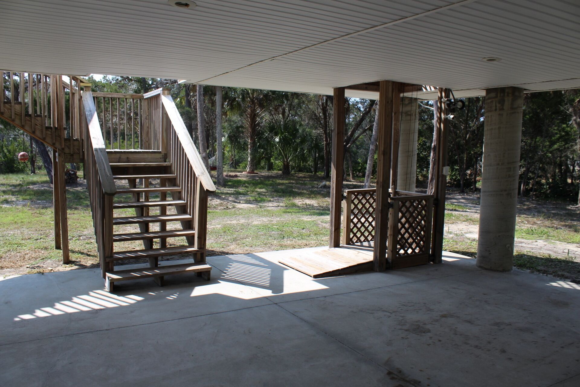Un espacio al aire libre cubierto con una escalera de madera que lleva a una plataforma, rodeado de árboles.