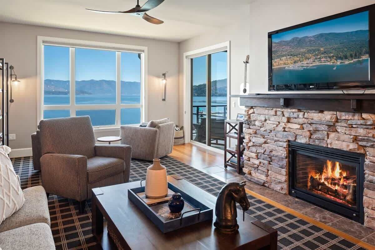 Un salon avec une cheminée, un grand téléviseur et une vue sur le lac.