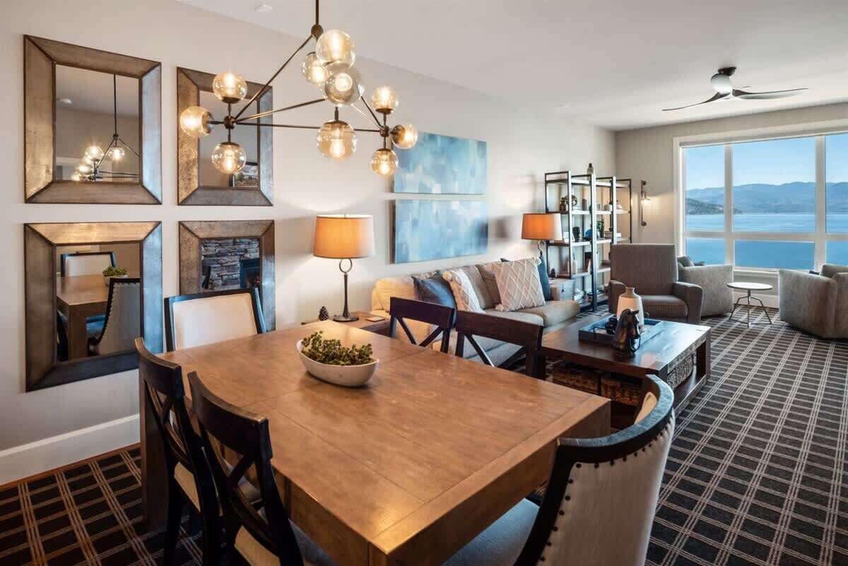 Une chambre d’hôtel moderne dotée d’un coin repas, d’un ensemble de canapés, d’une grande fenêtre offrant une vue agréable et d’un ventilateur de plafond.