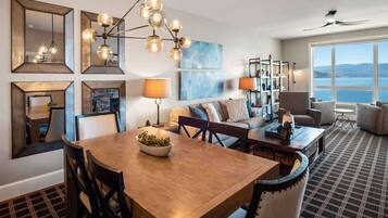 Une chambre d’hôtel moderne dotée d’un coin repas, d’un ensemble de canapés, d’une grande fenêtre offrant une vue agréable et d’un ventilateur de plafond.