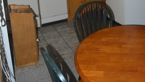 Een keuken met houten kastjes, een magnetron, een koffiezetapparaat, een spoelbak en een koelkast.