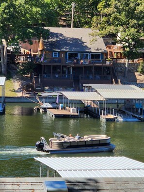 Une propriété au bord du lac, dotée d’un quai, d’un bateau et d’un bâtiment à plusieurs niveaux avec des balcons.