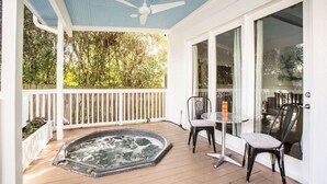 Un espacio al aire libre techado con jacuzzi, terraza de madera y una mesa con sillas.