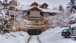 Een groot, meerijlaar boetiekhotel met een gevel van natuursteen en houten details, omringd door met sneeuw bedekte bomen.