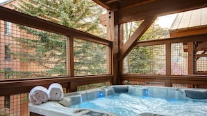 Een hottub met twee opgerolde handdoeken erop, omgeven door houten leuningen en een hekwerk van gaas.