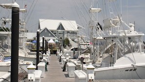 A marina with multiple boats docked, a covered walkway, and a building with a gabled roof. - 5-Star Oceanblock Sleeps 18! Luxury Beach Vacation Home Private Beach Community  (Bethany Beach)