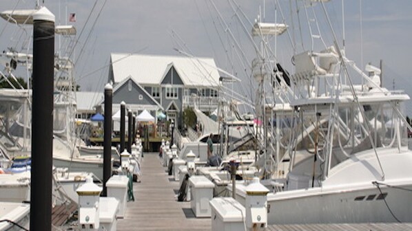 A marina with multiple boats docked, a covered walkway, and a building with a gabled roof.