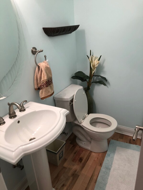 Un baño con lavamanos blanco, inodoro y una planta decorativa.