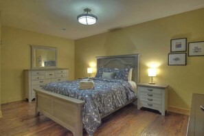 Un dormitorio con cama, mesitas de noche, cómoda y espejo.