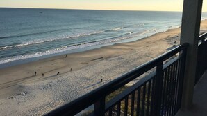 A beach with a clear view of the ocean and a few people walking along the shore. - Luxurious Oceanfront Condo- Right on the Beach (Windy Hill)