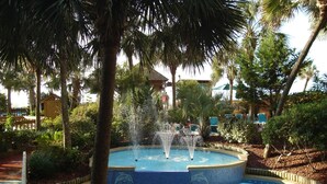 A swimming pool with a dolphin mosaic, surrounded by palm trees and a fountain. - Luxurious Oceanfront Condo- Right on the Beach (Windy Hill)