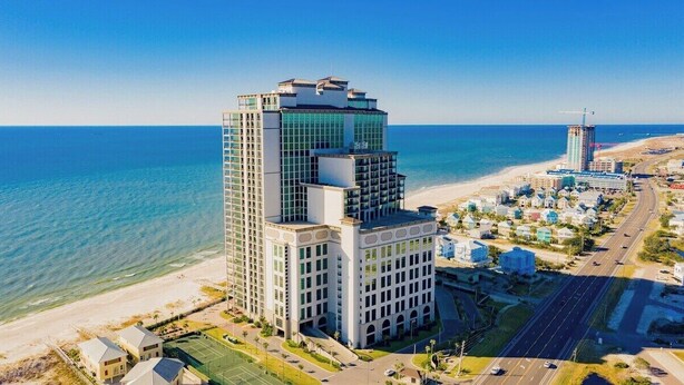 Un hotel moderno de gran altura, situado cerca de una playa con vistas despejadas al océano.