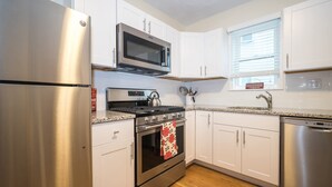 A modern kitchen with stainless steel appliances, white cabinets, and a wooden floor.