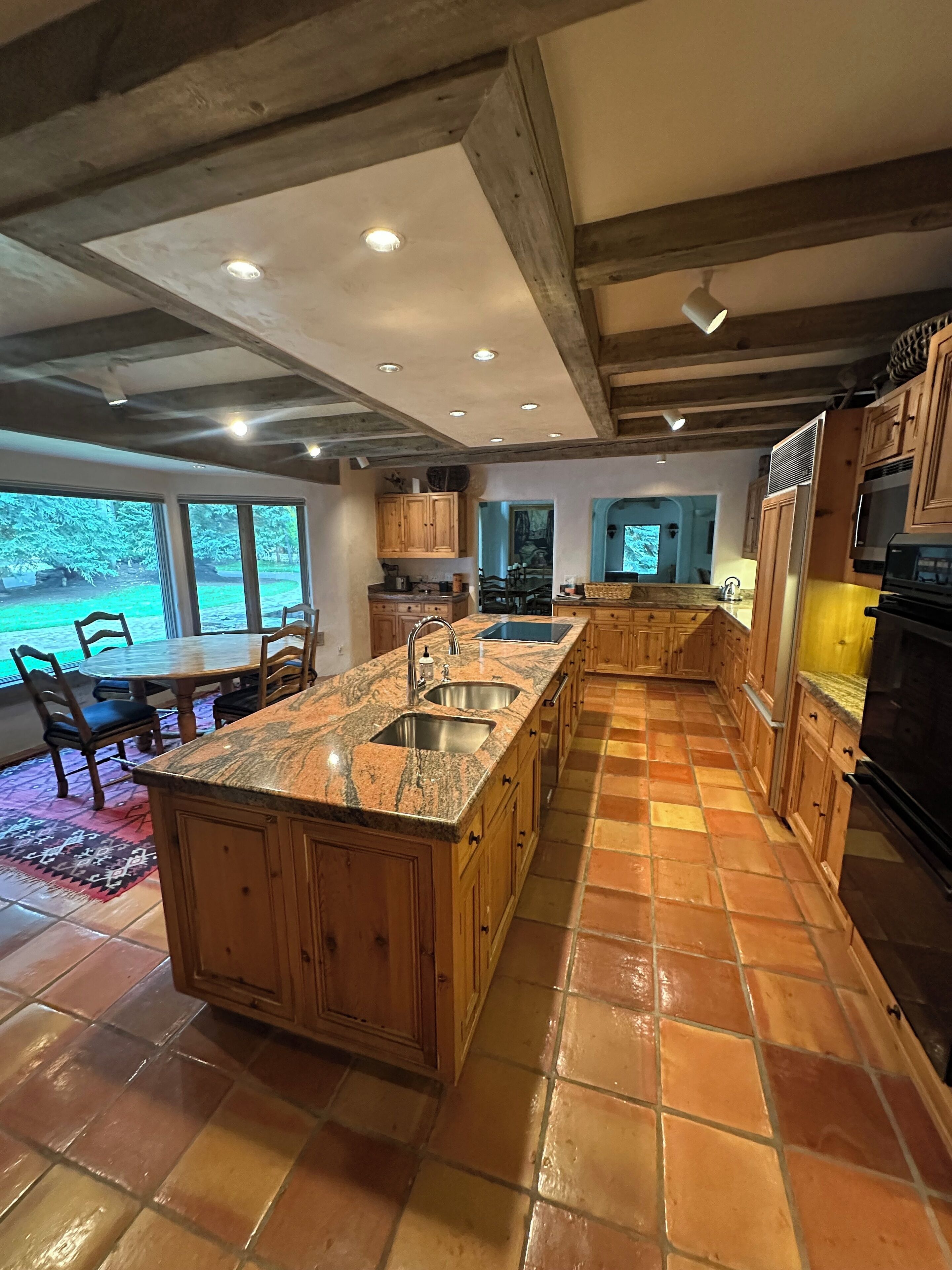 A spacious kitchen with a large island, wooden cabinets, and a tiled floor.