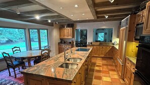 Una cocina amplia con una isla grande, armarios de madera y piso de baldosas.