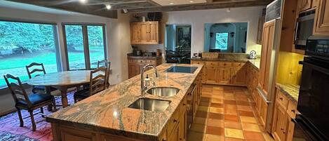A spacious kitchen with a large island, wooden cabinets, and a tiled floor.