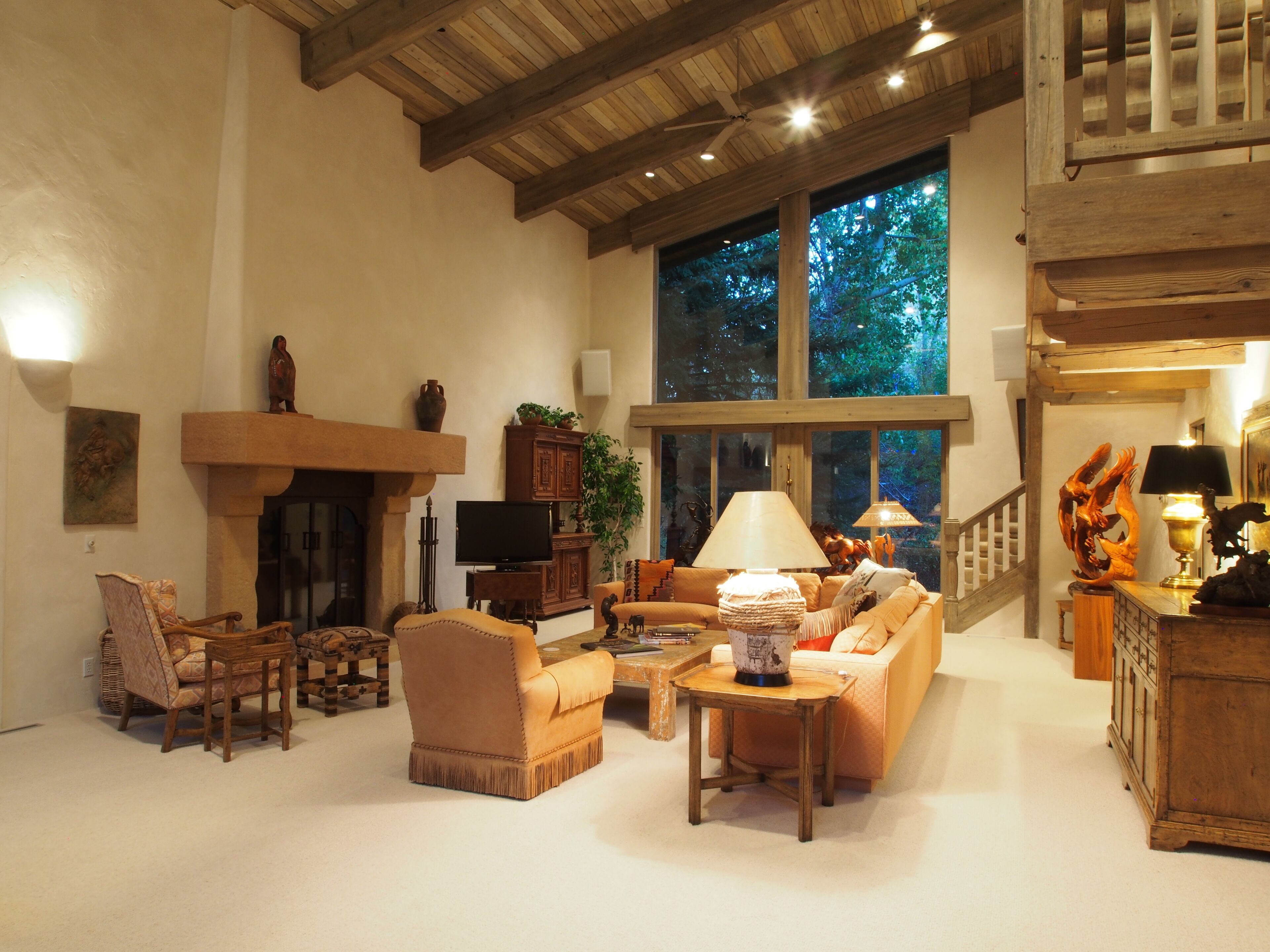 A spacious living room with a fireplace, comfortable seating, and large windows offering a view of the outdoors.