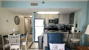 A compact living space with a kitchenette, dining area, and seating. - Beautiful Florida Condo in Oceanfront Building with River and Ocean Views (Daytona Beach Shores)