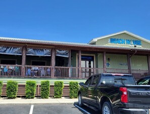 Un edificio con un letrero que dice "The Beach House" y una camioneta SUV estacionada.