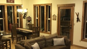 Een gezellige woonkamer met een bruine bank, een eettafel met stoelen en een bijzettafeltje.