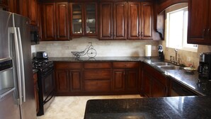A kitchen with dark wooden cabinets, stainless steel appliances, and a marble countertop. - VACATION HOME HAVE POOL & SPA / NEAR TO BEACHES-DISNEYLAND. (Huntington Beach)