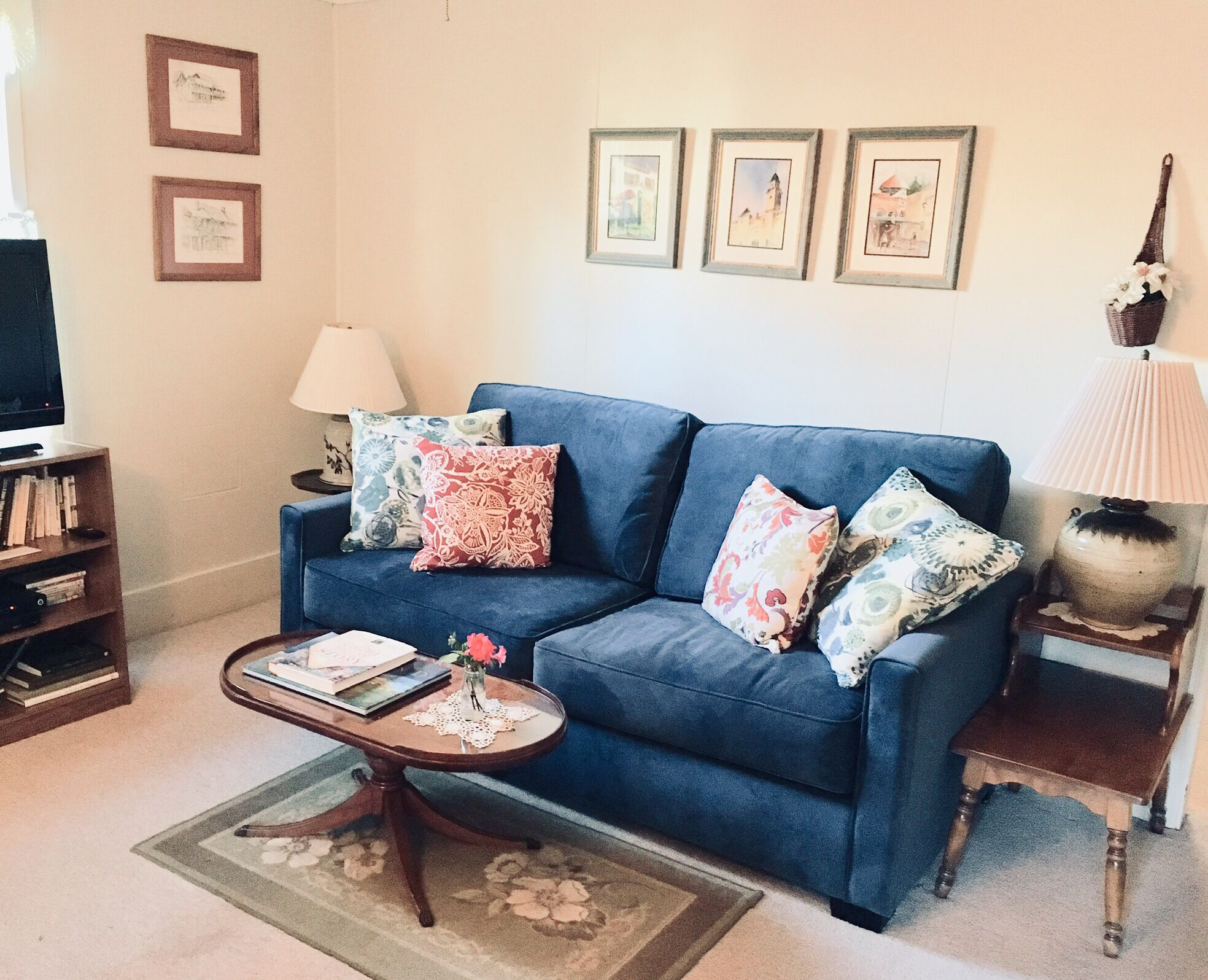 A living room with a blue sofa, a coffee table, a lamp, and framed pictures on the wall.