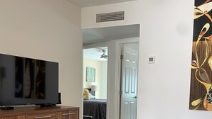 A modern living room with a flat-screen TV, wooden cabinet, glass coffee table, and a leather ottoman. - Desert Morada Casita G: 2 Bedroom 1 Bath Dog Friendly maximum 2-NO OTHER PETS (Tucson)