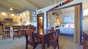 A compact hotel room with a dining area, kitchenette, and a bed with a view.