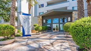 Entrada moderna de un hotel con un letrero azul y blanco, número 945, y un logo de brújula.