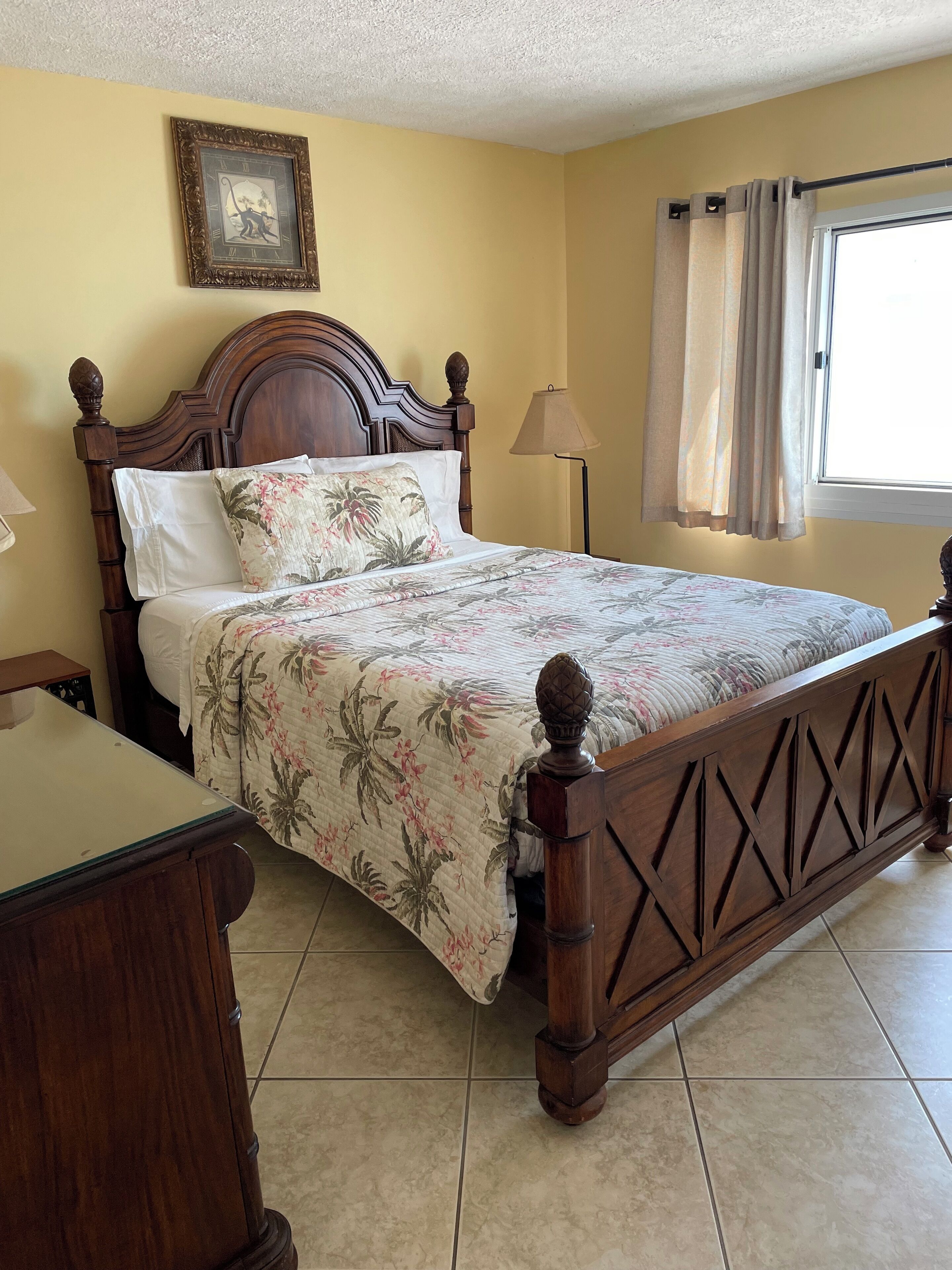 Una cama bien hecha con ropa de cama floral, un cabecero de madera y una mesita de noche.