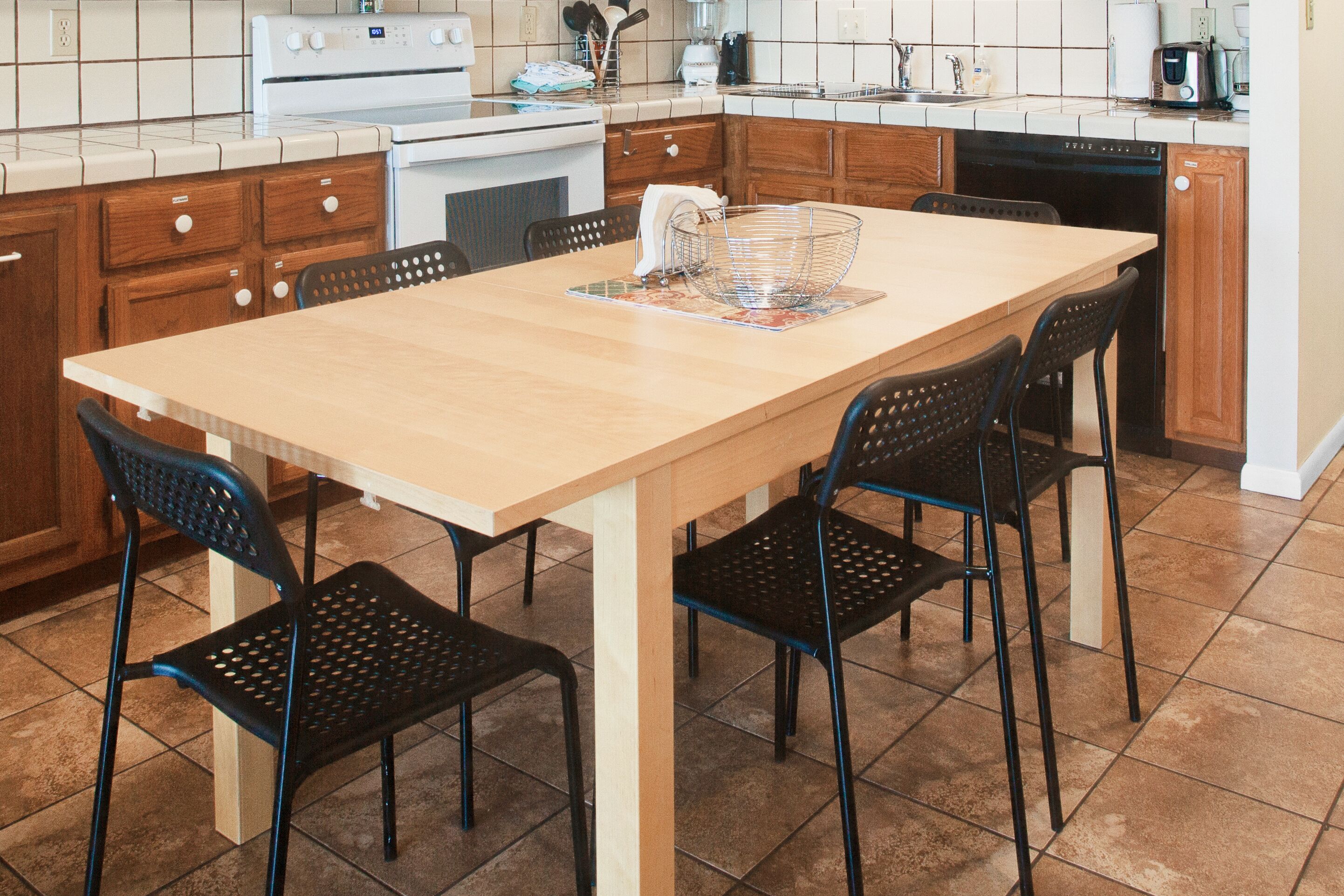 A kitchen with a wooden table and four chairs, a white stove, and a dishwasher.