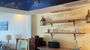 A dining area with a table, chairs, a decorative lamp, and a ceiling mural. - Beachbums Hideaway - Unique Artsy Beachfront Townhouse (Fort Walton Beach)