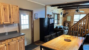 A kitchen with wooden cabinets, a black refrigerator, a dining table with chairs, and a staircase leading to a loft area. - Rustic and all the comforts of home in the Heart of the Elk Range (Benezette)