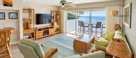 A spacious living room with a television, seating area, and a view of the ocean.