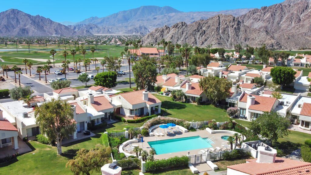 A residential area with houses, a swimming pool, and mountains in the background.
