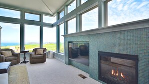 Une pièce spacieuse dotée de grandes fenêtres, d’une cheminée et de sièges confortables.