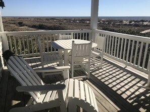 A wooden deck with a table and two Adirondack chairs, overlooking a beach. - Oceanfront /Spectacular Views/"OCEAN BEACH " (Bald Head Island)