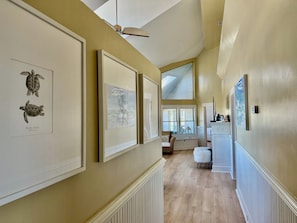 Stunning hallway with high ceilings, ceiling fan, and beautiful artwork adorns the walls.