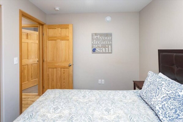 Un dormitorio con una cama, un armario de madera, una lámpara de pared y una frase inspiradora en la pared.