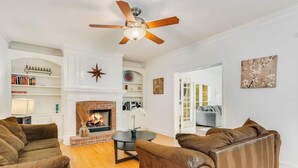 A living room with a fireplace, leather sofas, a ceiling fan, and a bookshelf. - Pool oasis with workspace, sleeps 10 (Conyers)