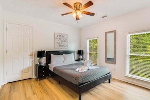 A bedroom with a bed, bedside tables, a ceiling fan, a window with blinds, and a door. - Pool oasis with workspace, sleeps 10 (Conyers)