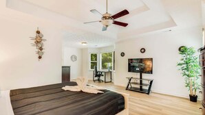 A modern bedroom with a bed, a ceiling fan, a TV, and a desk area. - Pool oasis with workspace, sleeps 10 (Conyers)