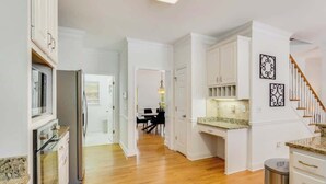A kitchen with white cabinetry, a stainless steel refrigerator, and a granite countertop. - Pool oasis with workspace, sleeps 10 (Conyers)