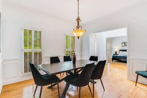 A dining area with a wooden table, black chairs, and a hanging light fixture. - Pool oasis with workspace, sleeps 10 (Conyers)
