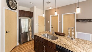 Una cocina moderna con refrigerador de acero inoxidable, encimera de granito y pileta doble.