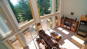 Un salon spacieux doté de grandes fenêtres, d’un coin salon confortable et d’une cuisine avec des meubles en bois.