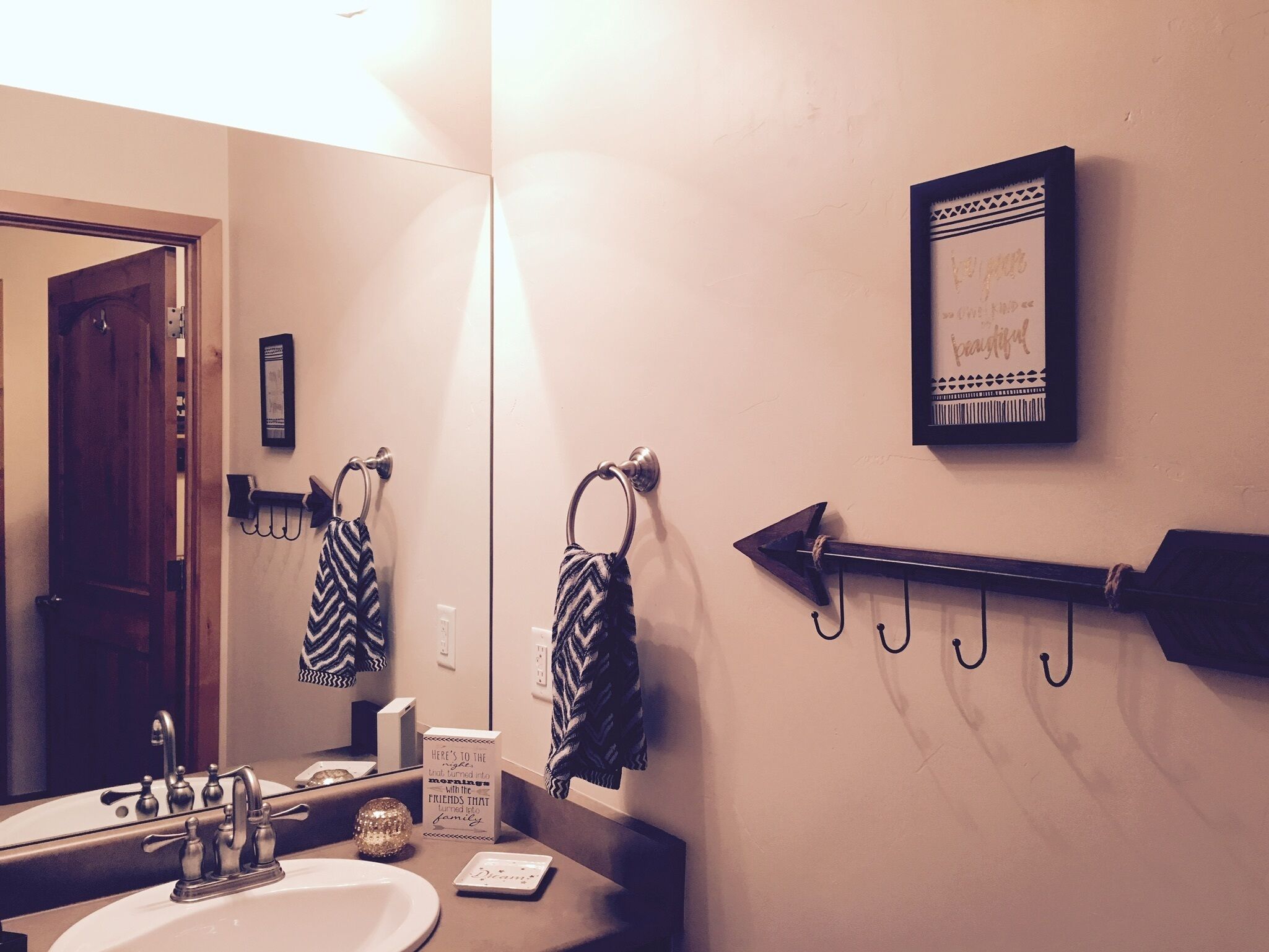 A bathroom with a sink, mirror, towel rack, and a framed inspirational quote on the wall.