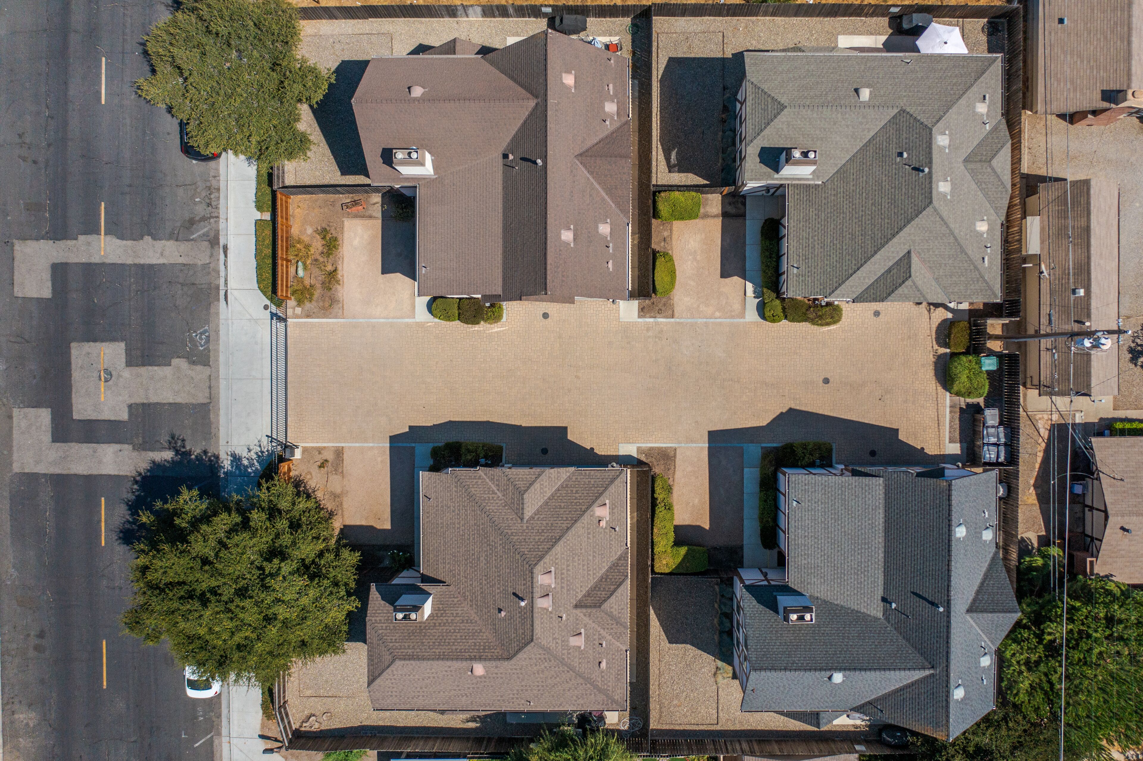 An aerial view of a residential area with four houses, each with a distinct roof design.