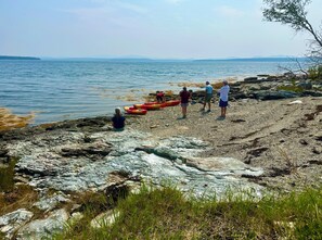 A rocky shoreline with kayaks and people.
