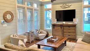 A living room with a sofa, armchair, coffee table, and TV stand. - Stunning five bedroom home with private pool, just steps from the beach! (Panama City Beach)